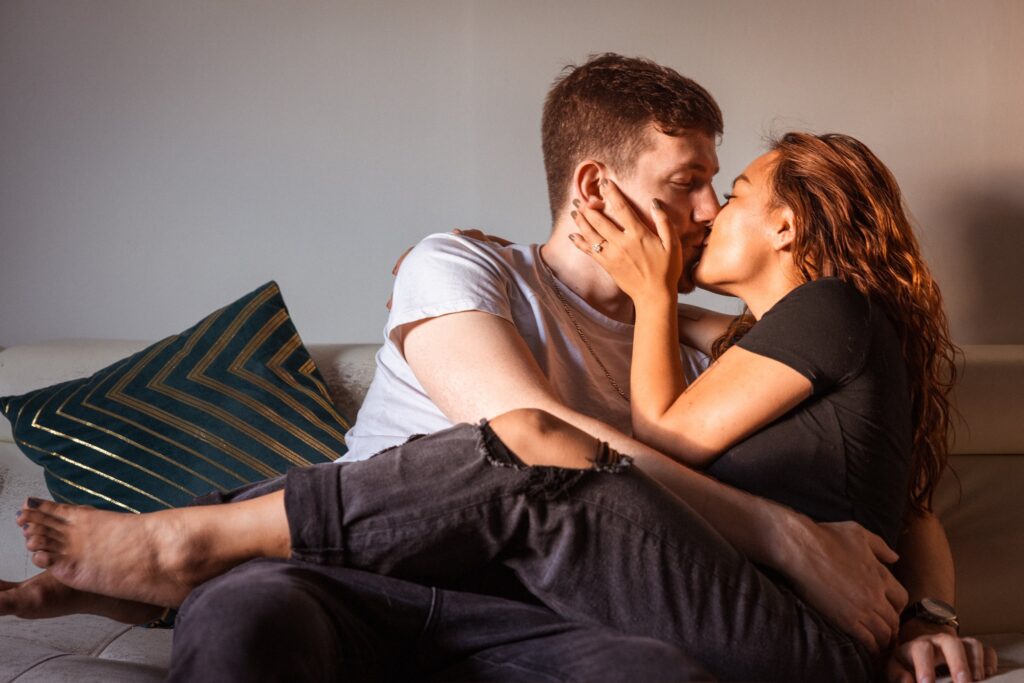 couple cuddles on couch during casual engagement photos at home