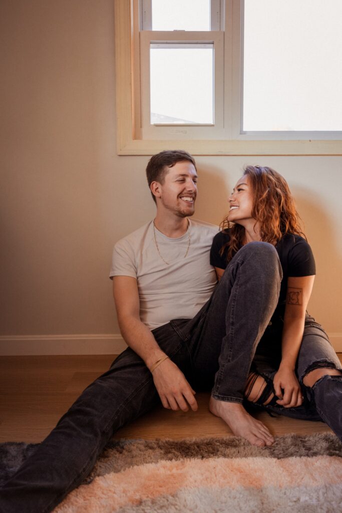 Couple smiles during engagement photoshoot at home
