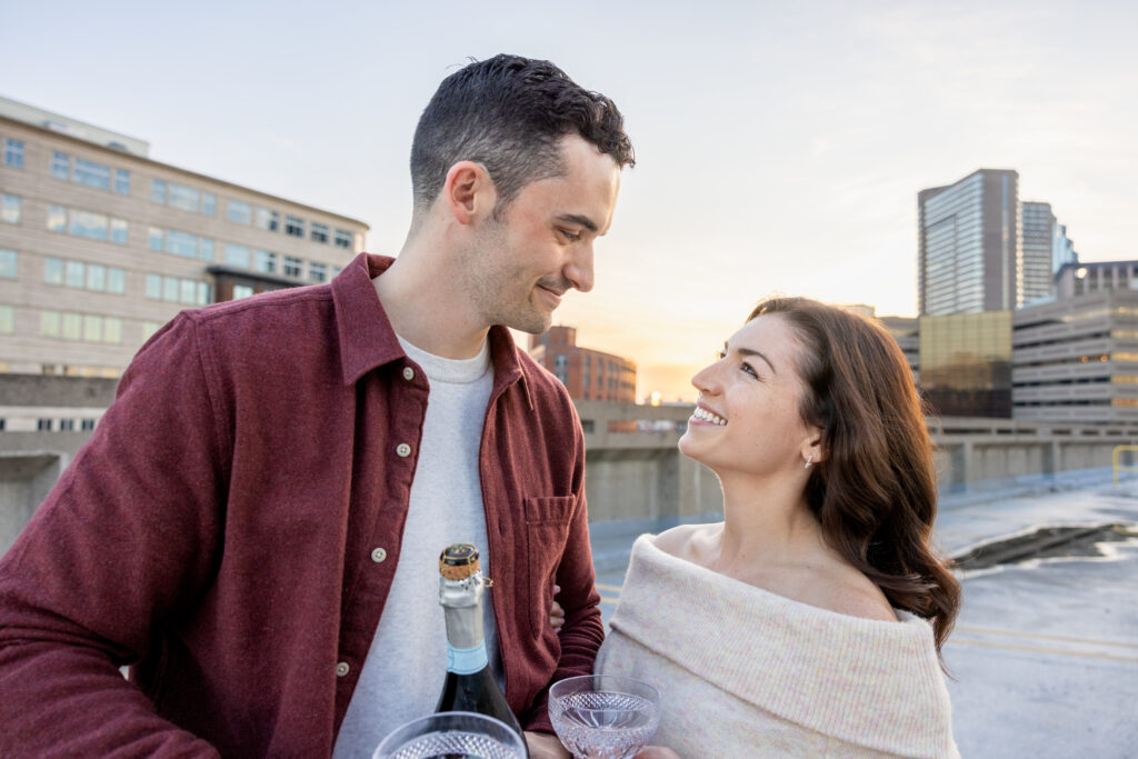 man and woman hold champagne glasses during engagement photos