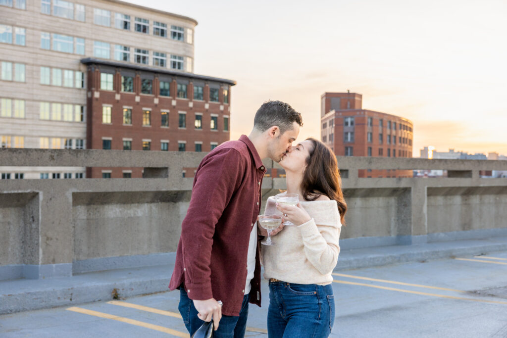 man and woman kiss on rooftop in Boston during engagement photos