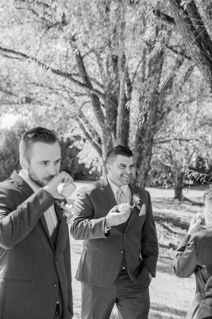 Candid moment of groomsmen eating apples at an apple orchard between photos