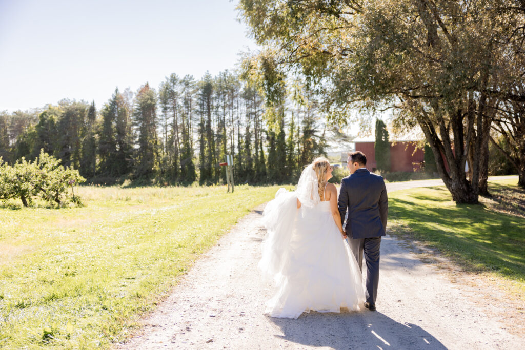 Bride and groom walking down a dirt road together to their ceremony