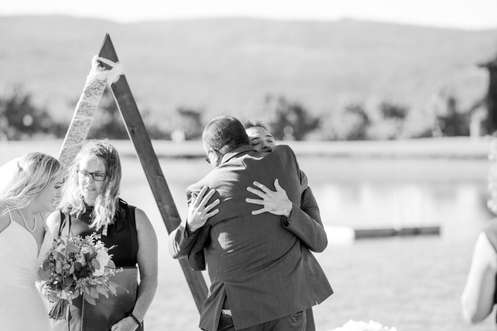 Bride’s father hugs his future son-in-law at the altar in black and white