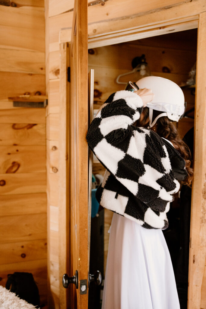 Bride putting on her snowboarding gear before their Vermont winter elopement