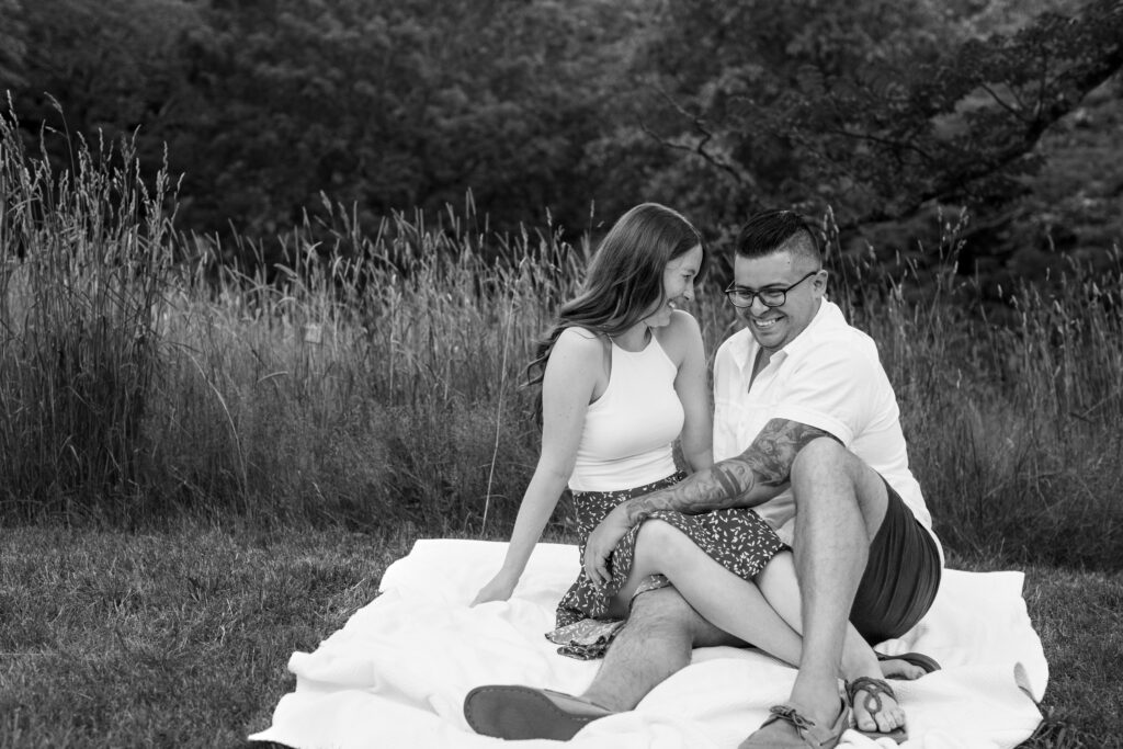 Engaged couple session at the Arnold Arboretum. Diverse Couple, engaged mixed couple black and white sitting down in front of a wheat field Candid moments engagement photos, engagement session, engagement shoot, engagement portrait