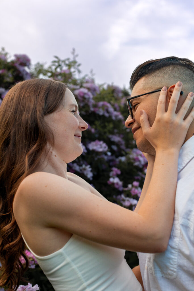 Engaged couple session at the Arnold Arboretum. Diverse Couple, engaged mixed couple, Candid moments of the couple portraits of their face and looking up cotton candy skies