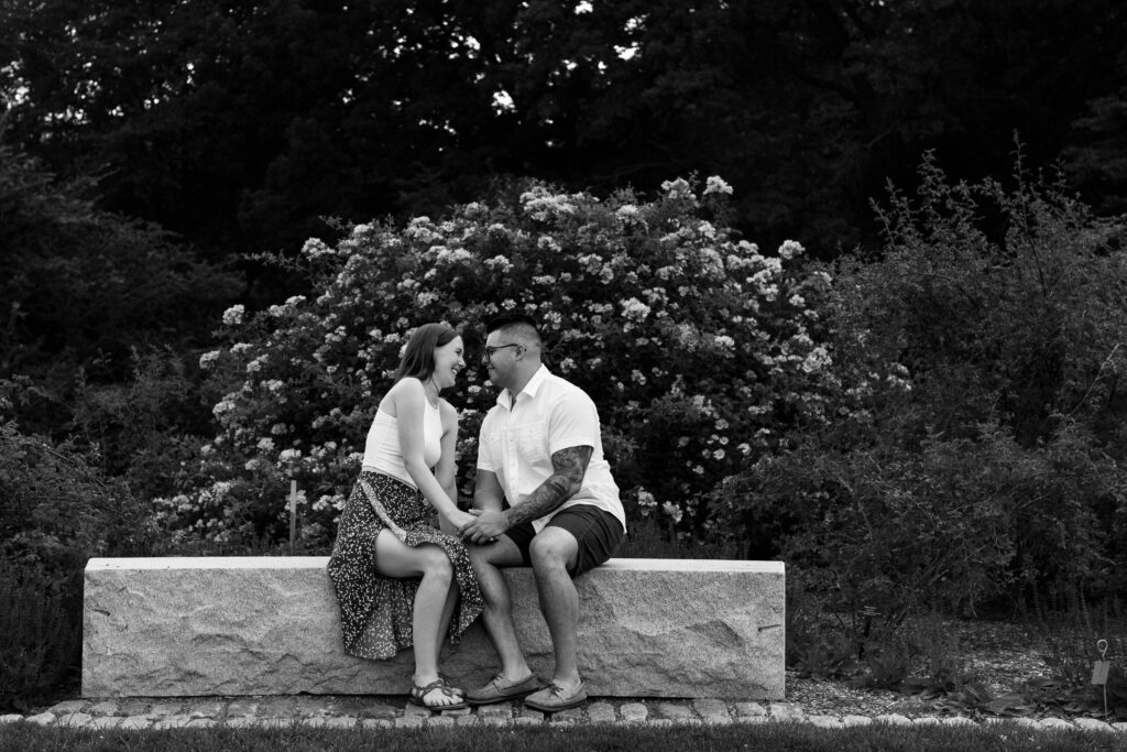 Engaged couple session at the Arnold Arboretum. Diverse Couple, engaged mixed couple, Candid moments of the couple sitting on a bench in black and white