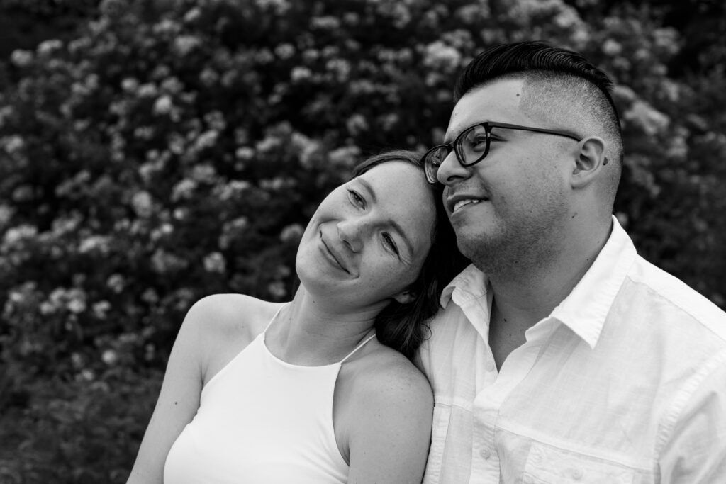 Engaged couple session at the Arnold Arboretum. Diverse Couple, engaged mixed couple, Candid moments of the couple sitting on a bench in black and white looking off into the distance