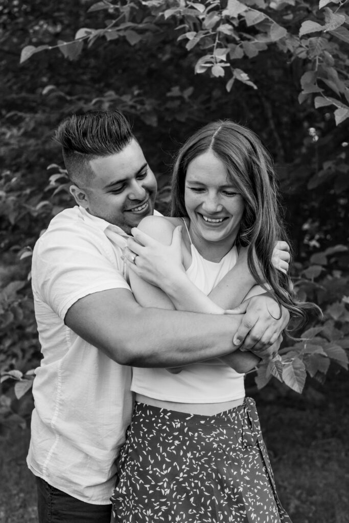 Engaged couple session at the Arnold Arboretum. Diverse Couple, engaged mixed couple, Candid moments of the couple hugging each other and having a laugh in black and white