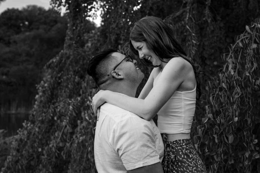 Engaged couple session at the Arnold Arboretum. Diverse Couple, engaged mixed couple, Candid moments of the couple having a romantic moment by the willow tree in black and white