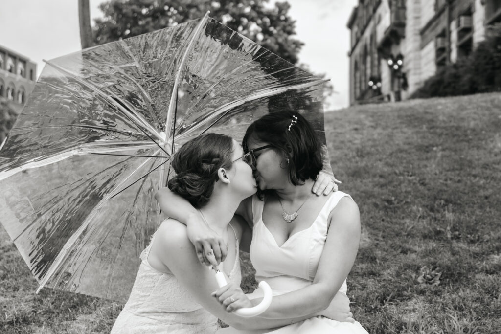 couple kisses under cute umbrella at Cambridge elopement