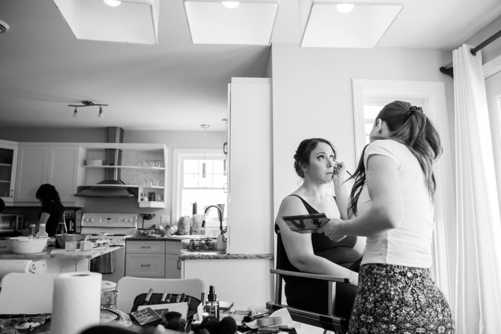 Bride getting her makeup done on her wedding day in the bridal suite in black and white
