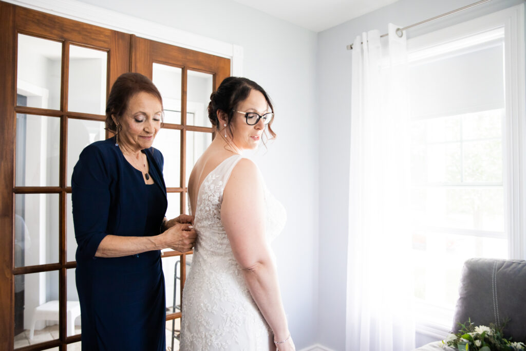 Bride’s mother helps her zip up her wedding dress