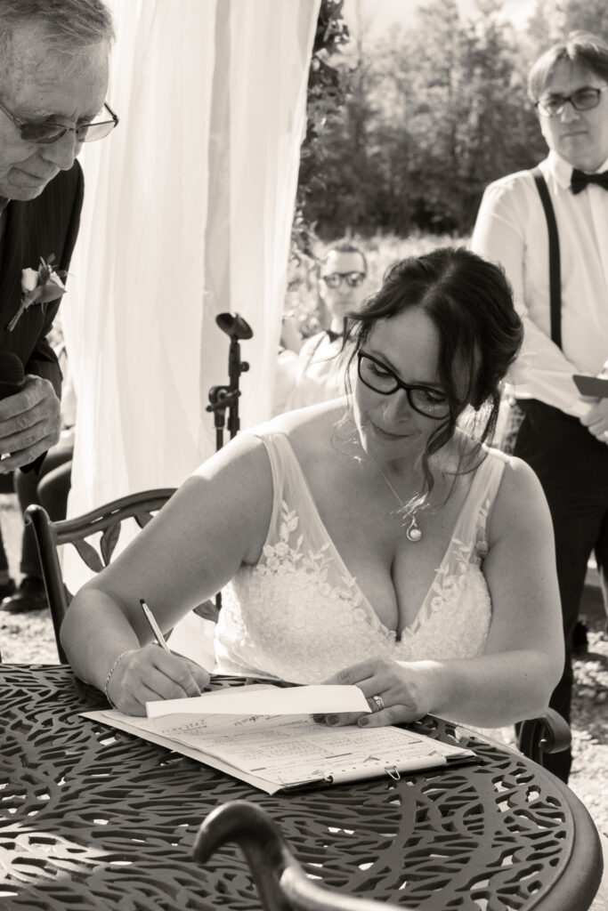 Bride signs her wedding certificate at the wedding ceremony In black and white