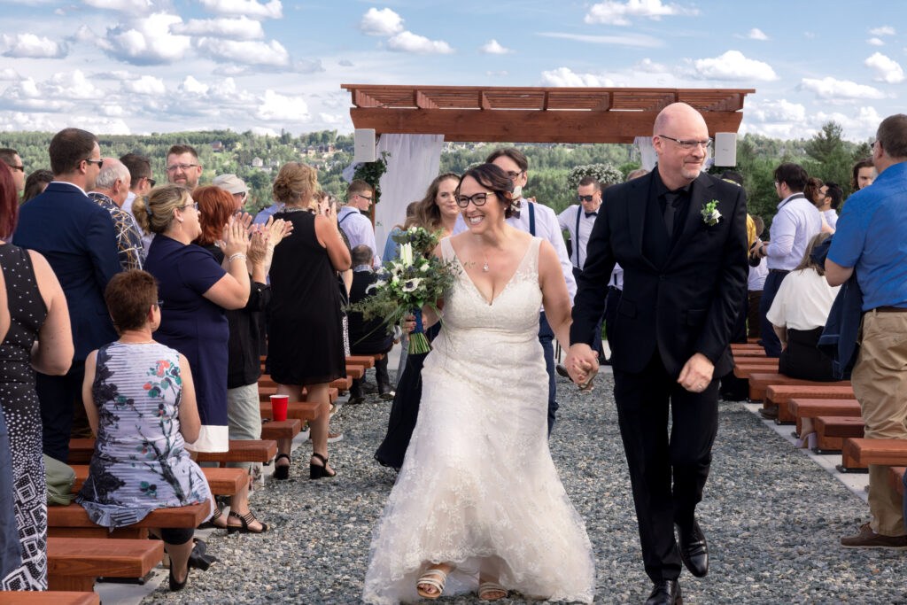 Bride and groom exit together during the recessional at their wedding with the crowd cheering them on