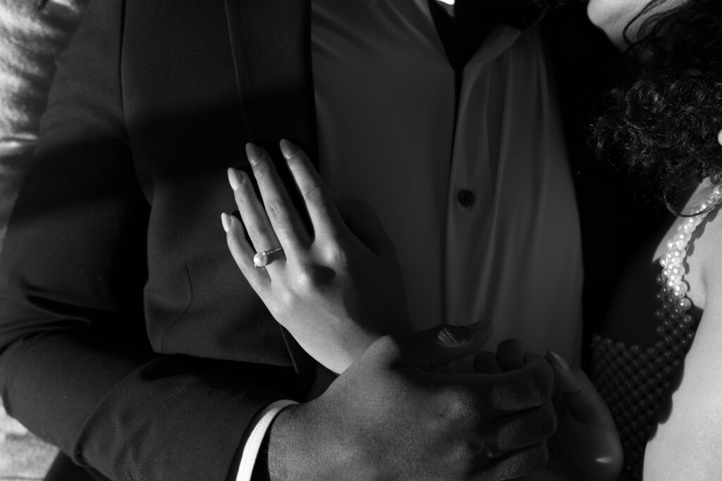 Bride’s hand on Groom’s chest with pearl ring detail shot