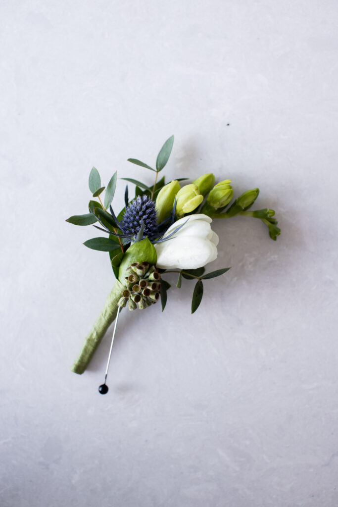 Boutonnière with anemone flower and blue thistle and greenery