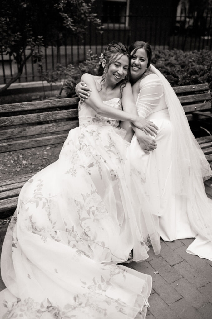 Two brides laugh and embrace on a bench after their wedding ceremony in Boston, captured on 35mm film by queer wedding film photographer Castillo Holliday Photo + Film