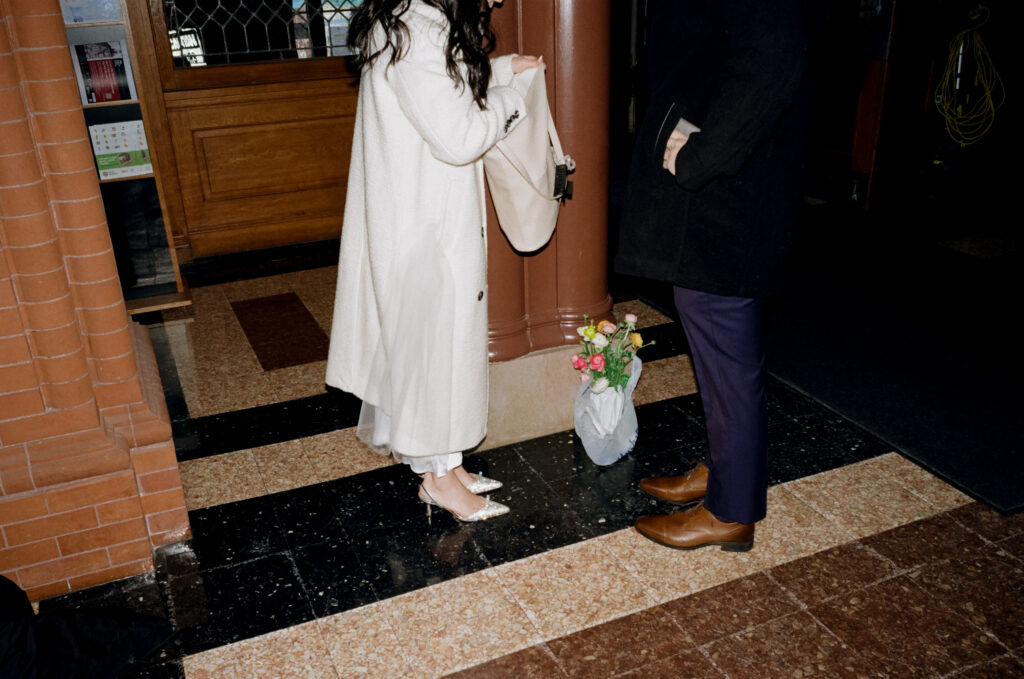 Documentary-style image of the couple waiting outside the clerk’s office inside Cambridge City Hall, taken on 35mm film.