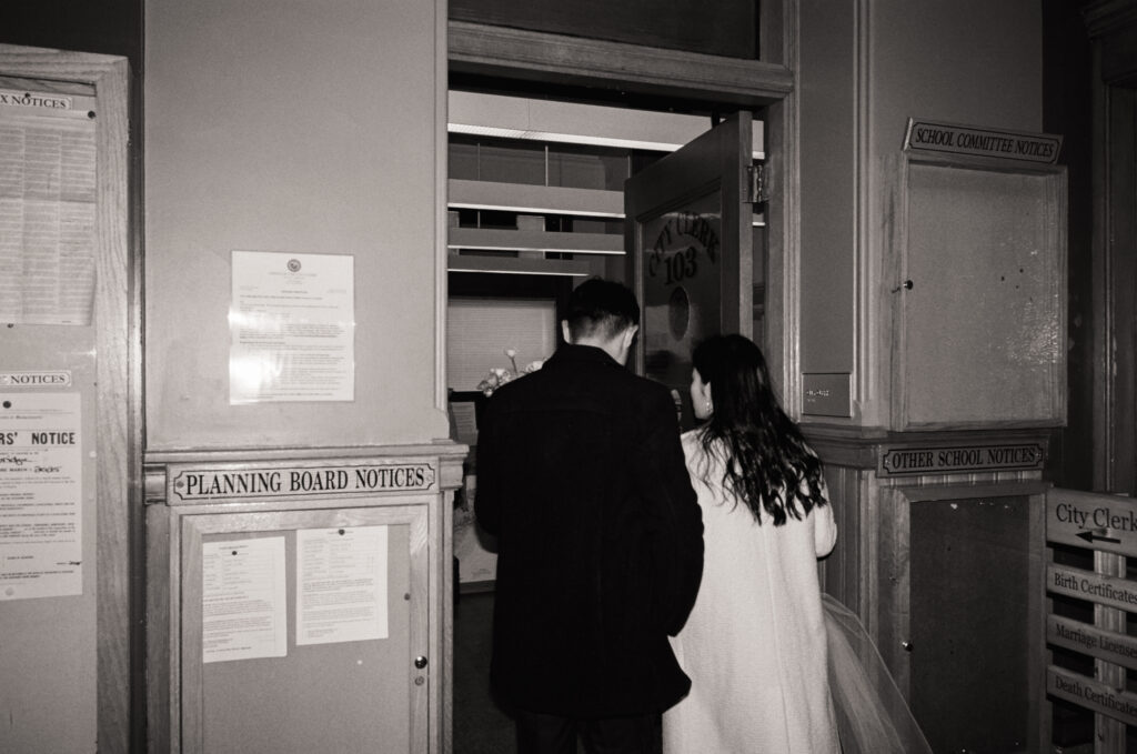 Documentary-style image of the couple waiting outside the clerk’s office inside Cambridge City Hall, taken on 35mm film.