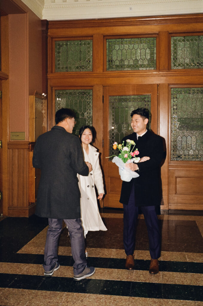Documentary-style image of the couple waiting outside the clerk’s office inside Cambridge City Hall, taken on 35mm film.