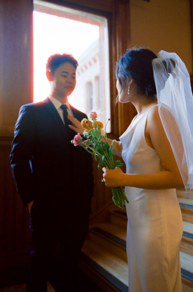 Soft, honest image of Anna adjusting Huimin’s collar before their ceremony at Cambridge City Hall—captured on Kodak film.