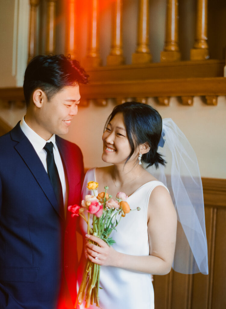 Film photo of the couple laughing quietly together inside Cambridge City Hall before exchanging vows.