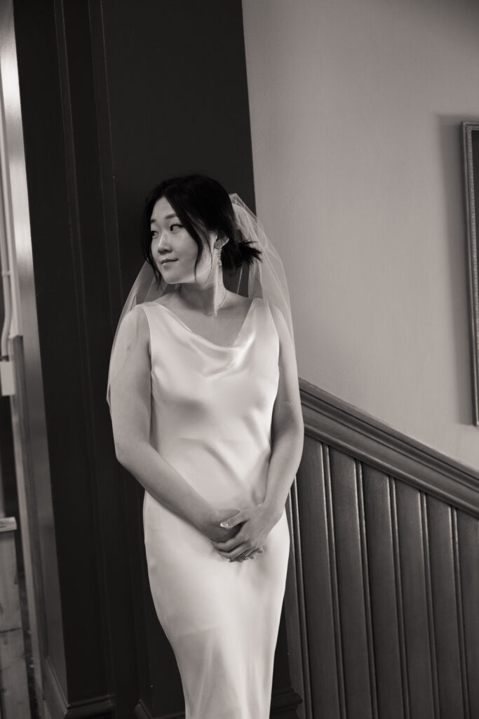 Film photo of Anna in her elopement dress, standing alone in the historic interior of Cambridge City Hall