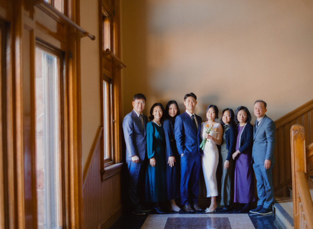 Family photo of Anna and Huimin with their parents and siblings inside Cambridge City Hall during their Boston elopement, photographed on film.