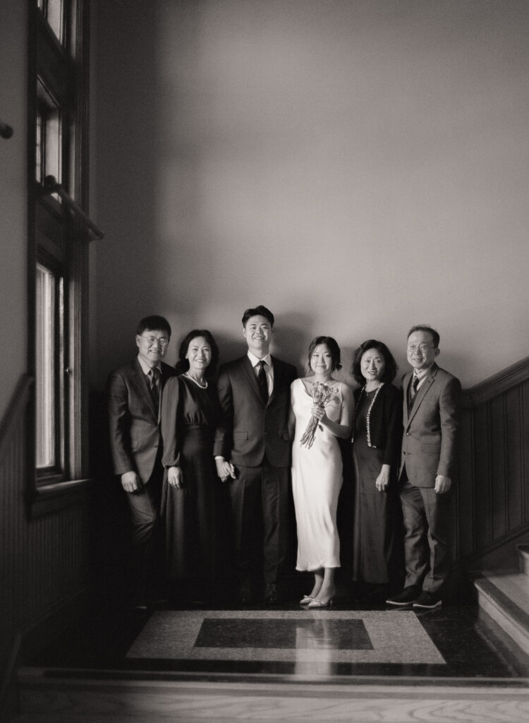 Group portrait of newlyweds Anna and Huimin with both families before their Cambridge City Hall ceremony, captured by a Boston film elopement photographer.