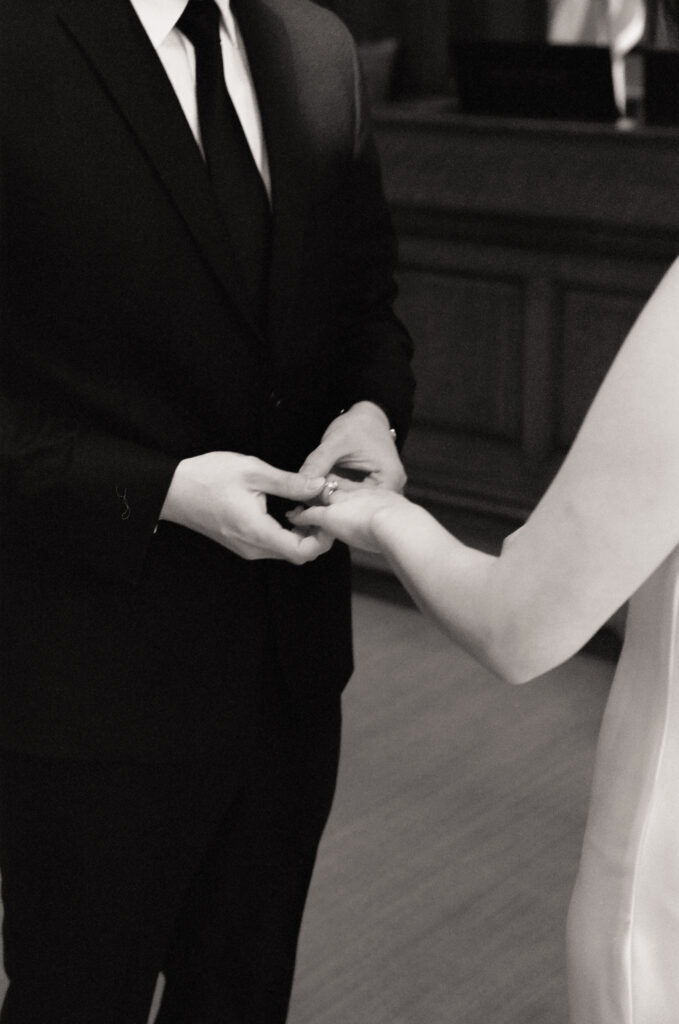 Anna and Huimin standing hand in hand inside Cambridge City Hall as they say “I do” on Valentine’s Day.