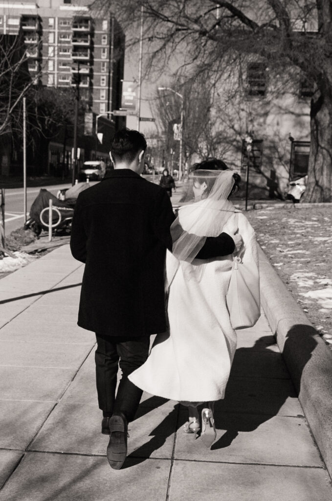 Bride and groom smiling and exiting Cambridge City Hall after their elopement, photographed on film.