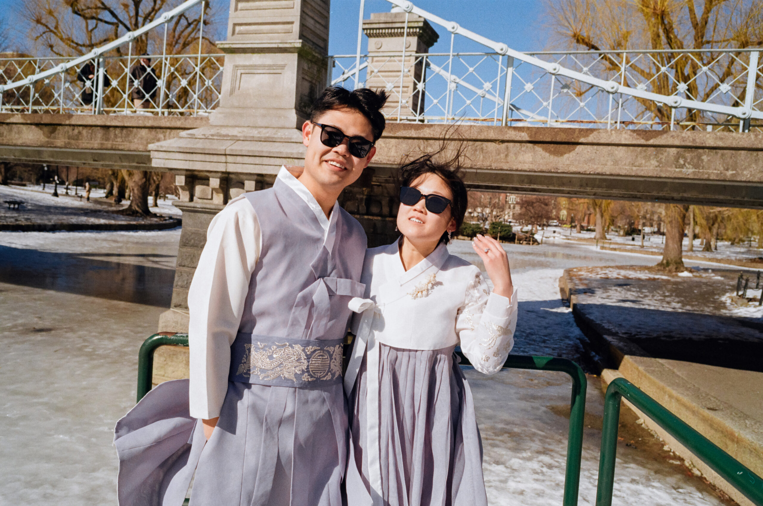 Couple laughing near frozen pond in Boston Public Garden during winter elopement.