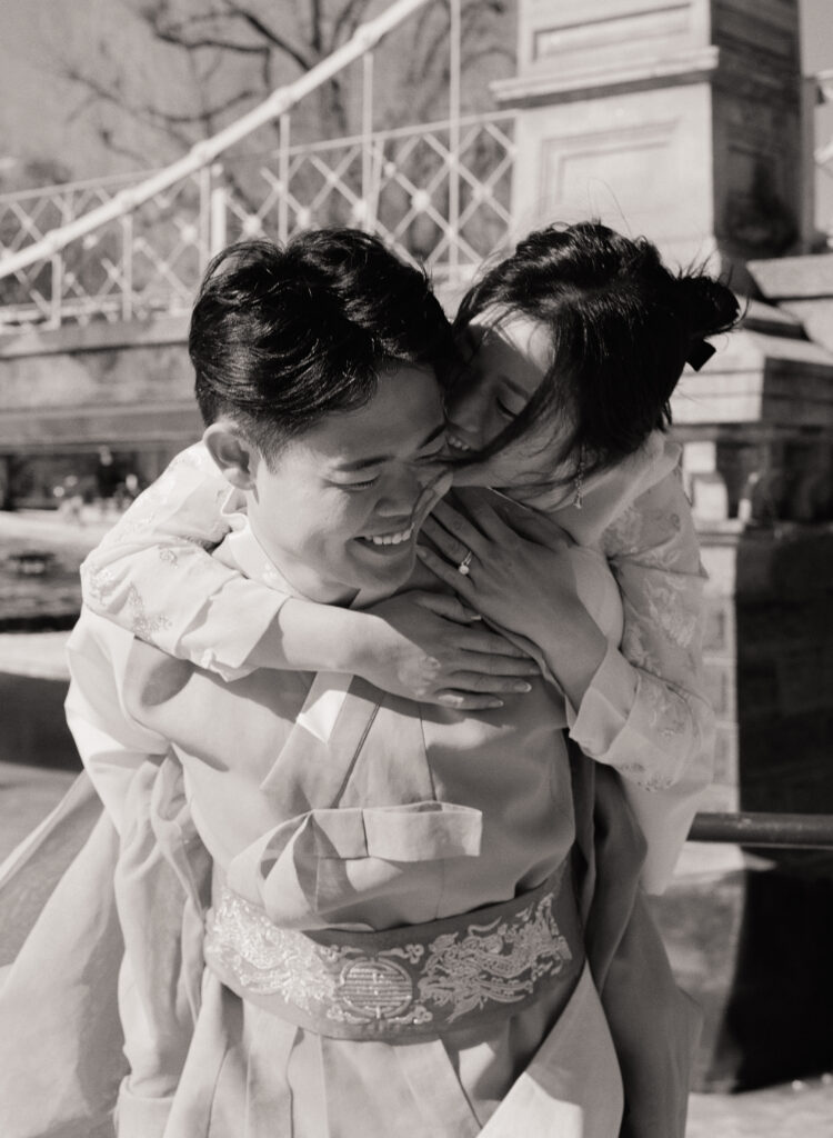 Couple laughing near frozen pond in Boston Public Garden during winter elopement.