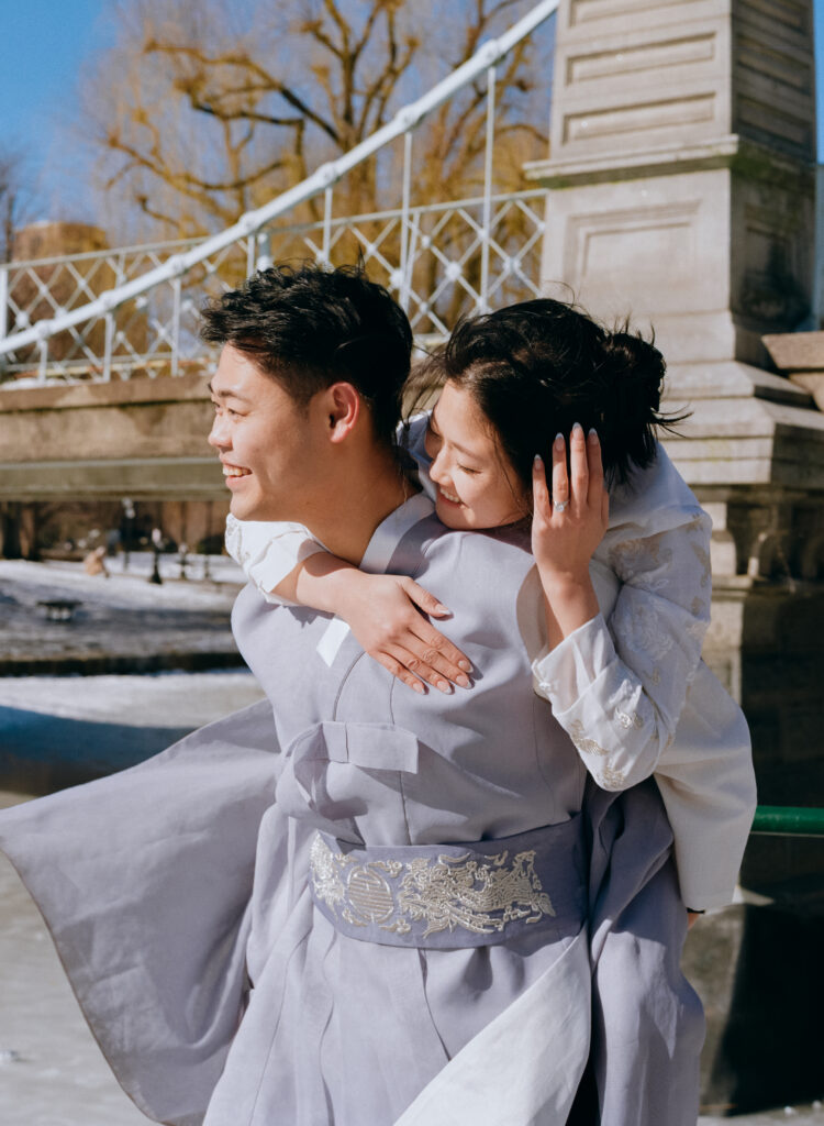 Couple laughing near frozen pond in Boston Public Garden during winter elopement.