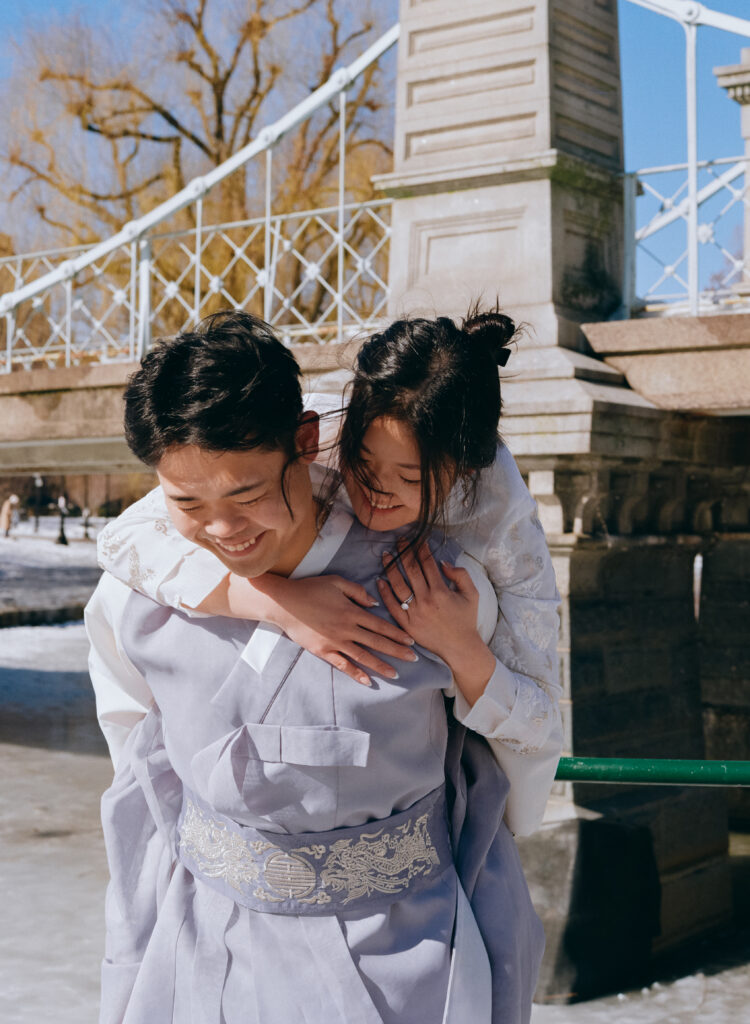 Couple laughing near frozen pond in Boston Public Garden during winter elopement.