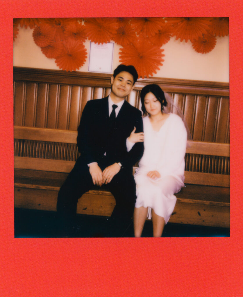 Polaroid photo of newlyweds Anna and Huimin sitting together inside Cambridge City Hall, moments after their elopement ceremony—captured on film by a Boston elopement photographer.