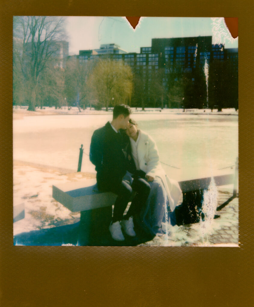 Couple laughing near frozen pond in Boston Public Garden during winter elopement on polaroid film.
