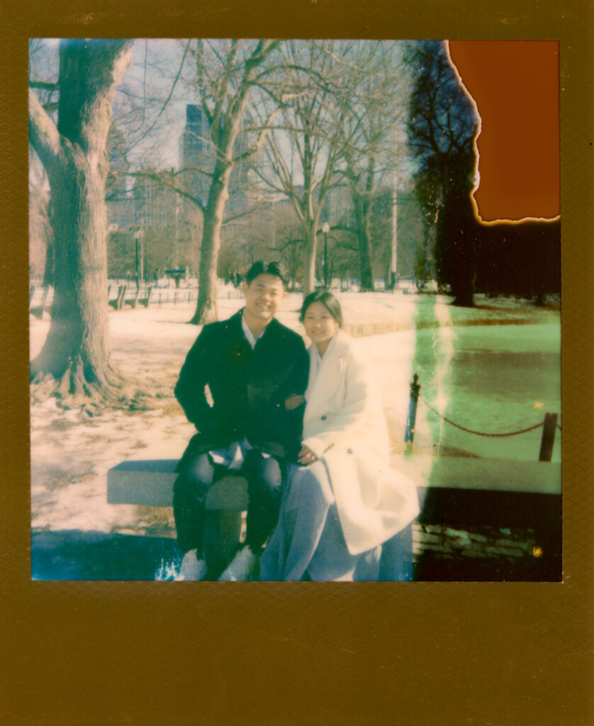 Couple laughing near frozen pond in Boston Public Garden during winter elopement on polaroid film.