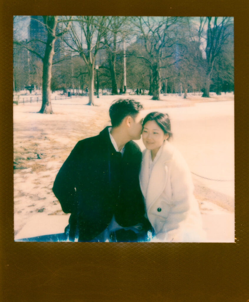 Couple laughing near frozen pond in Boston Public Garden during winter elopement on polaroid film.