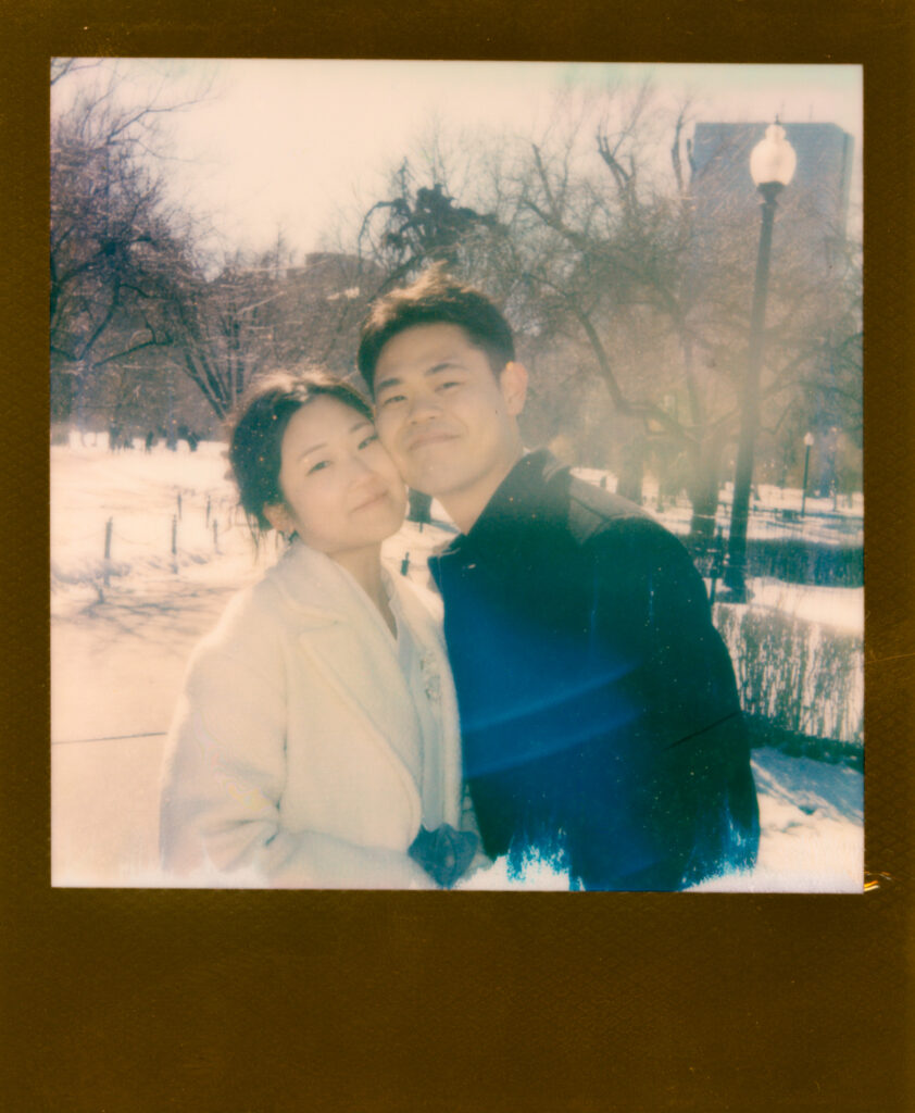 Couple laughing near frozen pond in Boston Public Garden during winter elopement on polaroid film.
