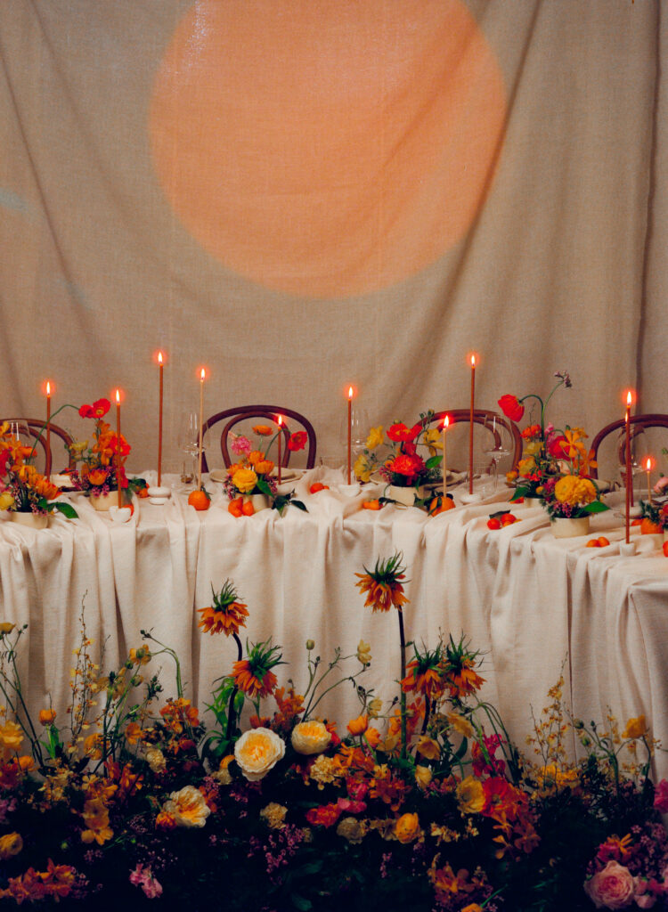 Citrus-toned spring wedding reception table with floral ground installation and candlelit details. A romantic wedding design captured entirely on film by a New England film wedding photographer.