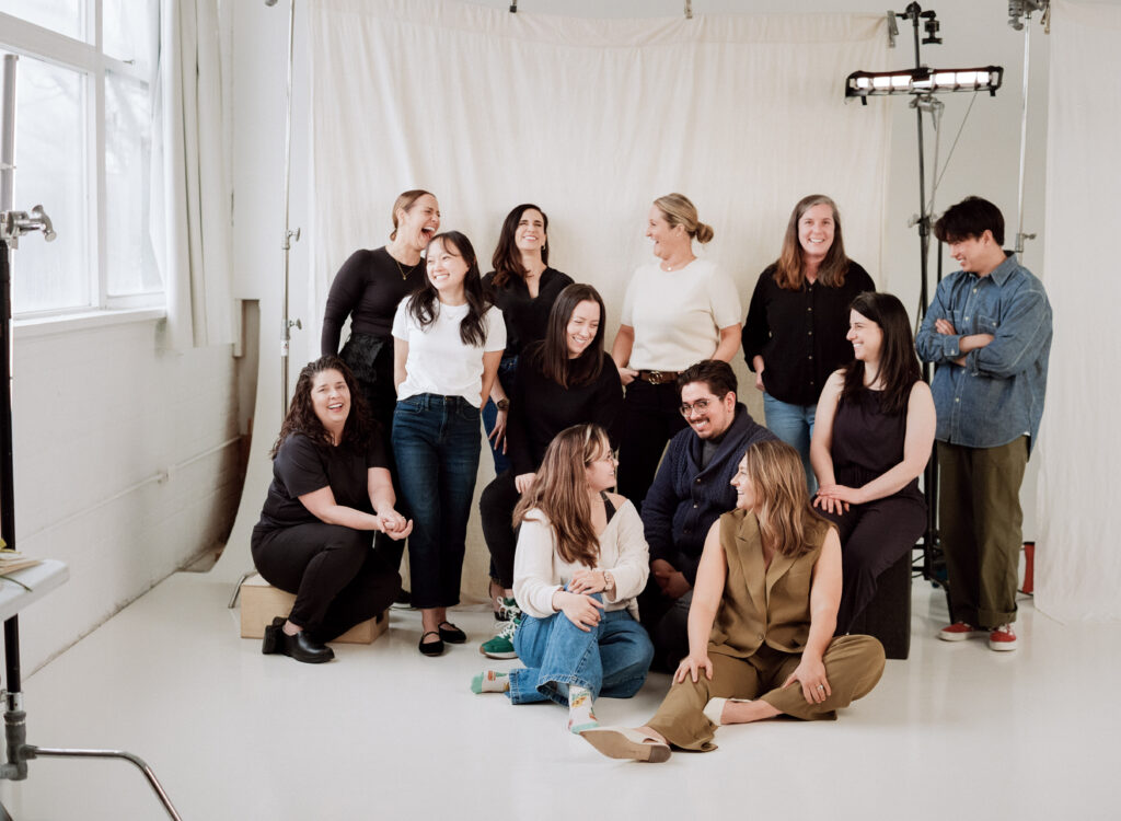 Diverse wedding vendor team laughing together during a creative editorial photoshoot in a Boston studio. Behind-the-scenes moment featuring planners, florists, stylists, filmmakers, and creatives from the Spring 2025 wedding editorial by Castillo Holliday Photo + Film.