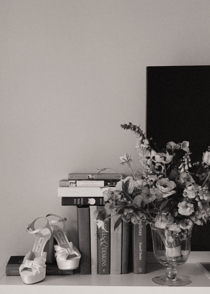 Bride’s Jimmy Choo heels styled with fresh florals and vintage books – detail shot at Winnetu Oceanside Resort wedding in Edgartown.
