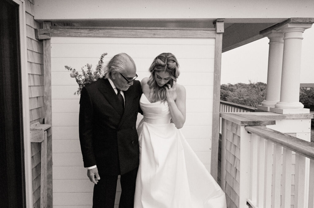 Bride shares a quiet first-look moment with her father on a porch in Martha’s Vineyard, both looking down with emotion before the ceremony.