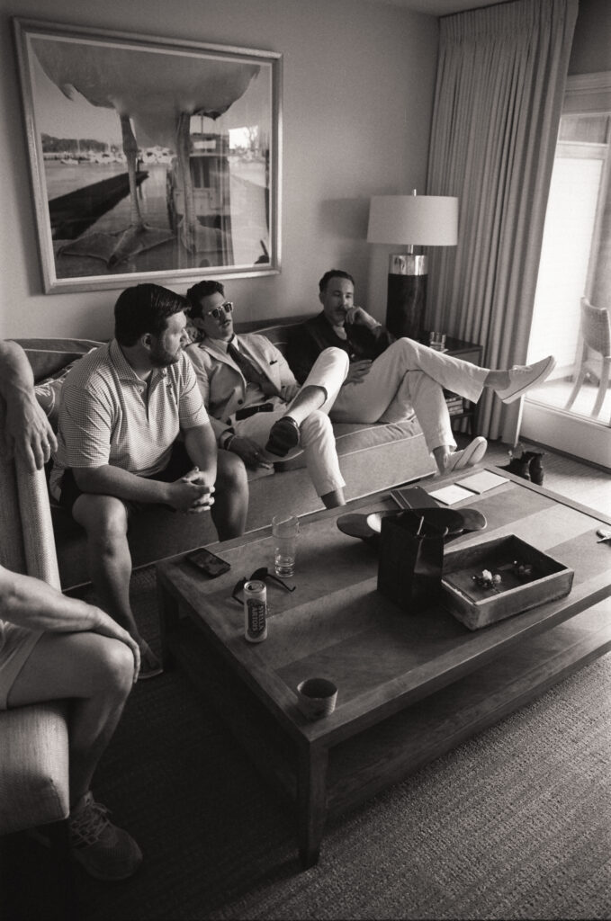 Candid film photo of the groom and friends sitting together in a hotel room before the ceremony.