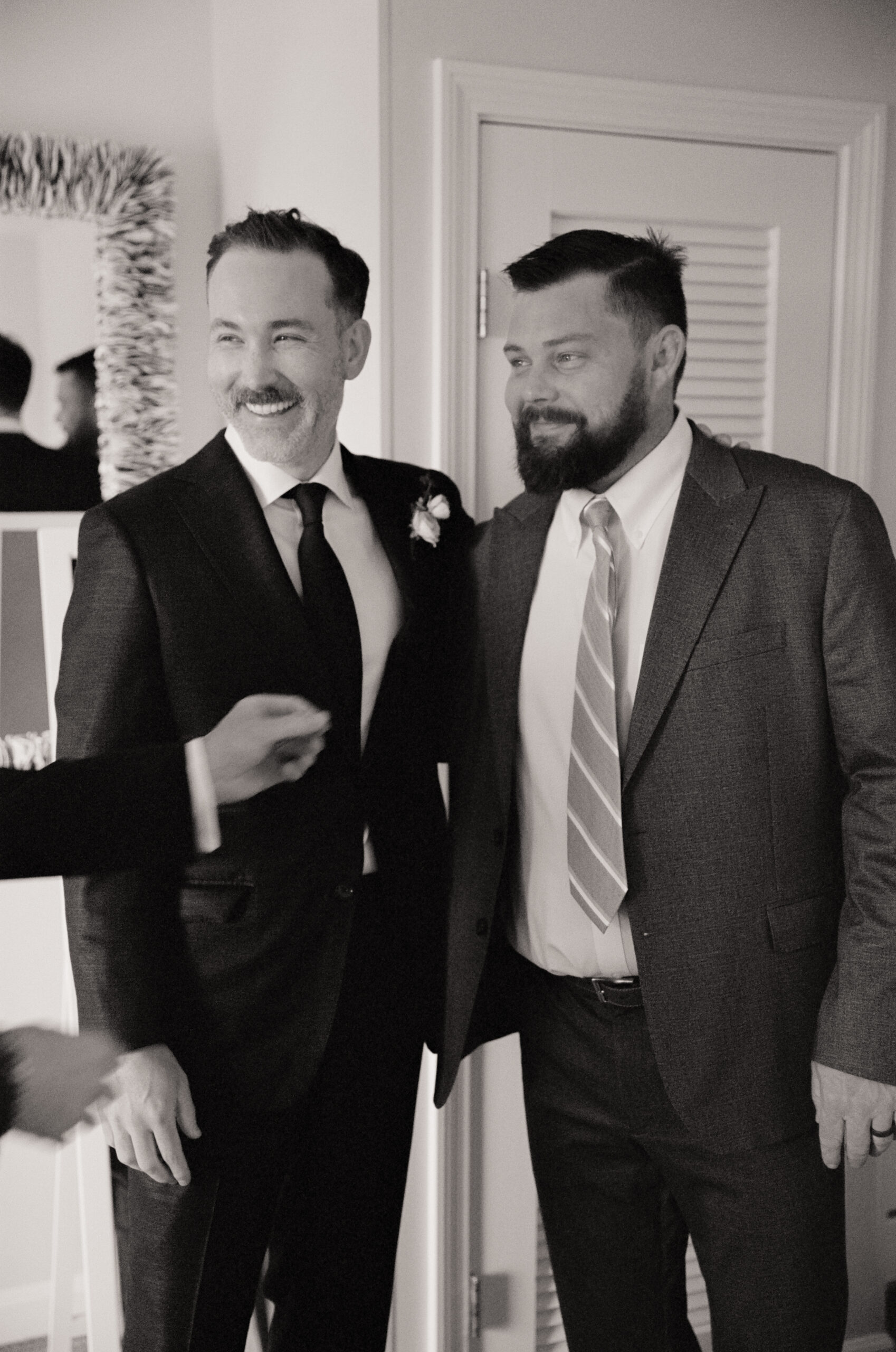 Black and white wedding film portrait of the groom and his groomsman in suits.