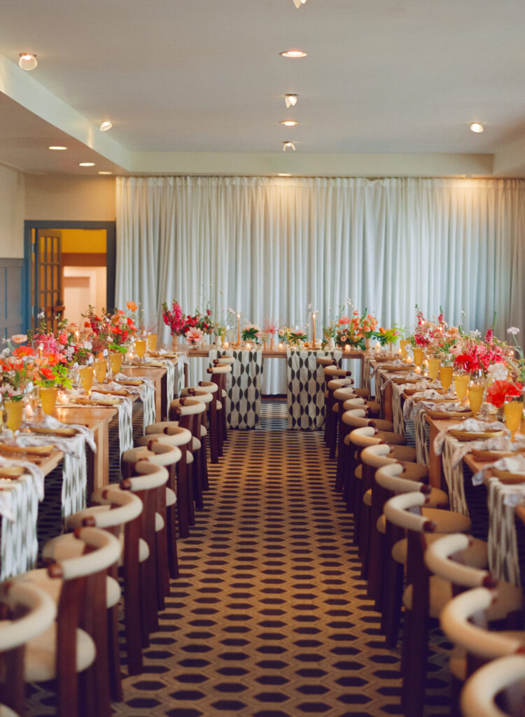Wide view of modern reception hall with long tables decorated with bright florals and candles in Martha’s Vineyard.
