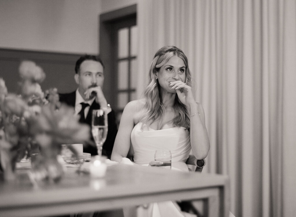 Bride in a strapless gown reacting emotionally during speeches at her Martha’s Vineyard wedding dinner.