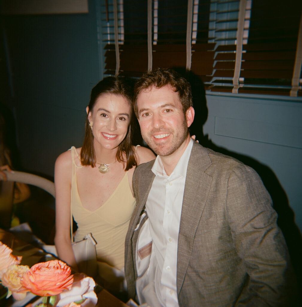 A man and woman seated at a table, engaged in conversation over drinks.